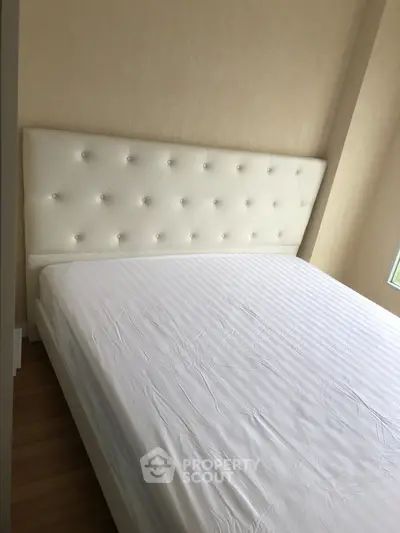 Spacious bedroom with elegant white tufted headboard and natural light