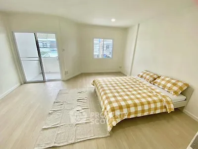Spacious bedroom with large windows and balcony access, featuring a cozy bed and minimalist decor.