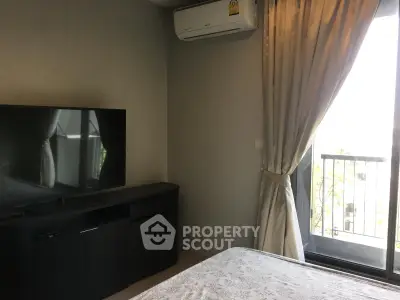 Modern bedroom with balcony access and sleek TV setup, perfect for urban living.