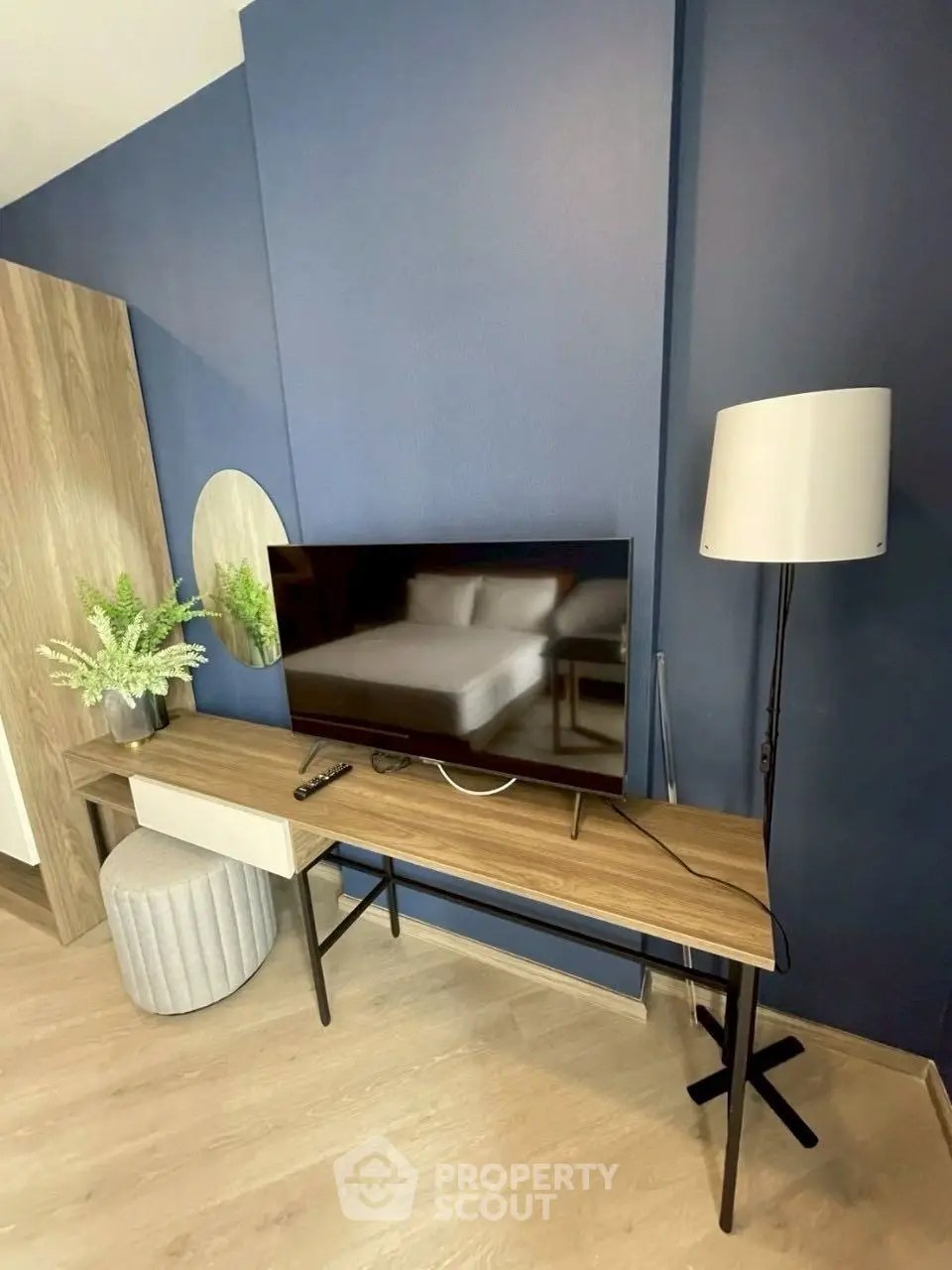 Modern living room with stylish TV stand and floor lamp, featuring a sleek blue accent wall.
