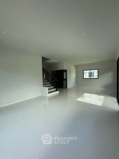 Spacious modern living room with glossy white tiles and staircase