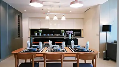 Modern dining area with elegant table setting and stylish kitchen in open layout apartment.