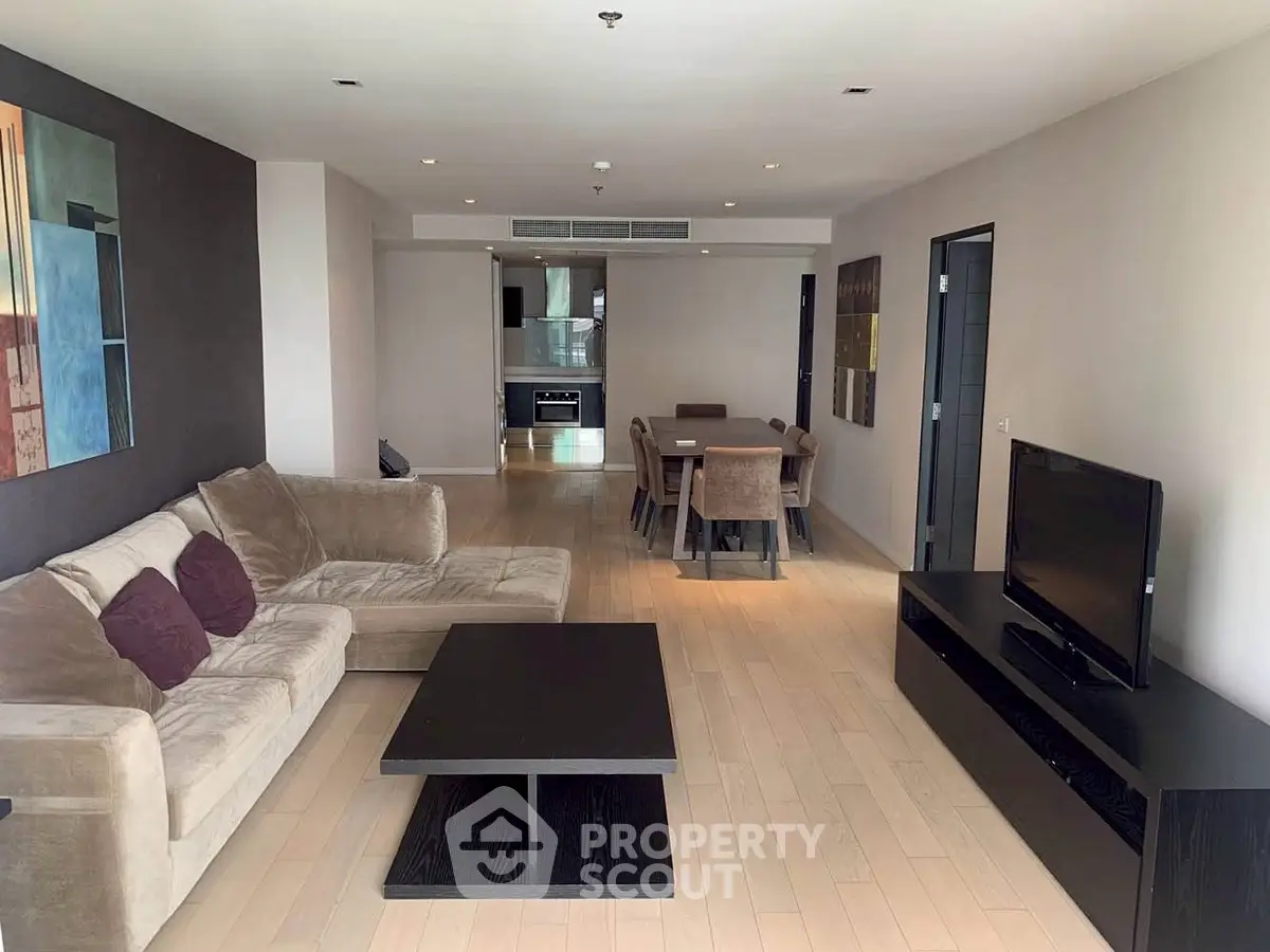 Spacious modern living room with elegant decor and open layout, featuring a cozy sofa and sleek entertainment center.