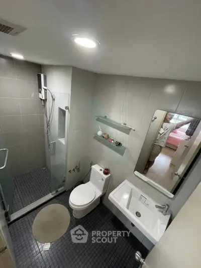 Modern bathroom with glass shower, sleek fixtures, and neutral tiles in a contemporary apartment.