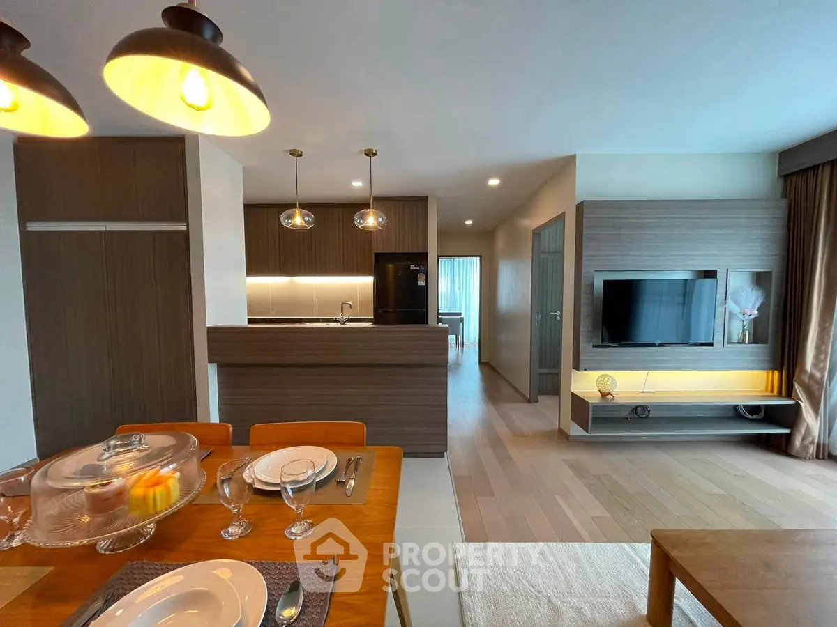 Modern open-plan living room with stylish kitchen and dining area, featuring elegant lighting and contemporary decor.