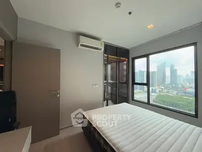 Modern bedroom with city view, featuring sleek design and large window for natural light.