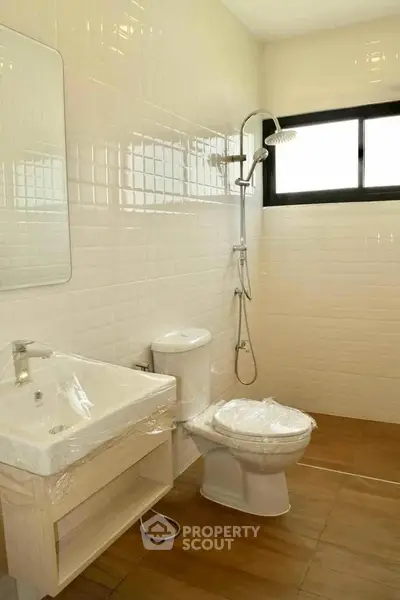 Modern bathroom with sleek fixtures and natural light, featuring a shower and elegant tile design.