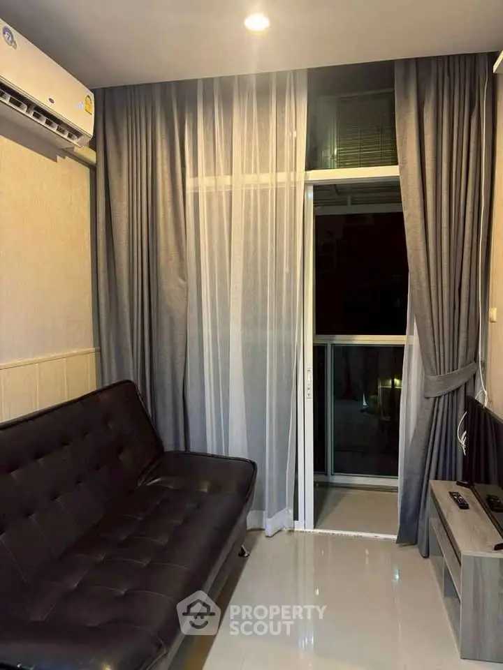 Modern living room with sleek black sofa and floor-to-ceiling curtains, featuring a balcony view.