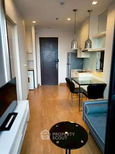 Modern open-plan living room with kitchen, featuring sleek design and wooden flooring.