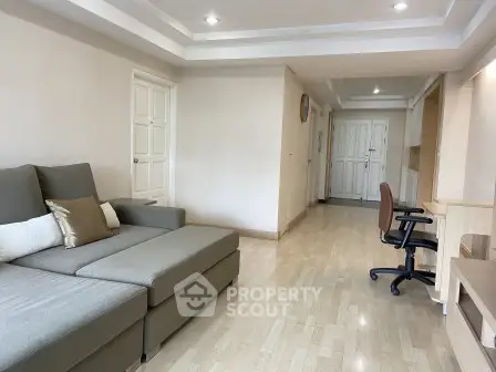 Spacious living room with modern sofa and study area in a bright apartment.