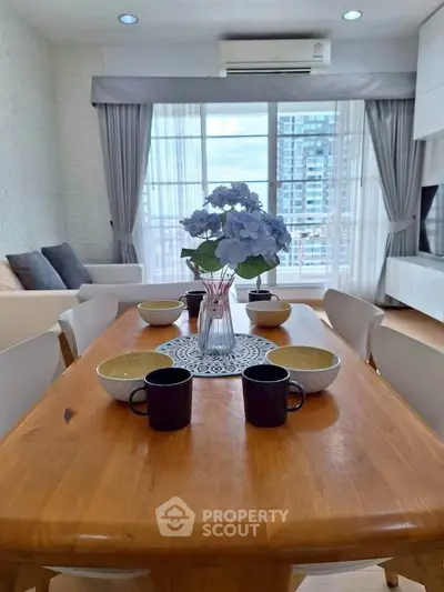 Bright and airy living room with dining area, featuring modern decor and large windows with city view.