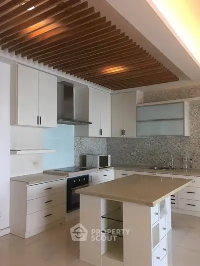 Modern kitchen with sleek cabinetry, island, and stylish ceiling design in a contemporary home.