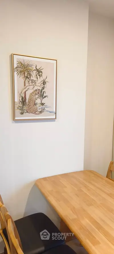 Cozy dining area with wooden table and chairs, featuring elegant wall art for a warm ambiance.