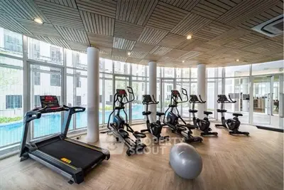 Modern gym with state-of-the-art equipment and pool view in luxury apartment complex.