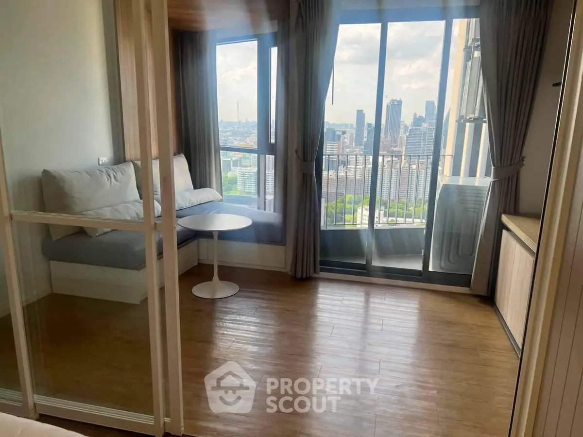 Modern apartment with stunning city view and cozy seating area by large windows.