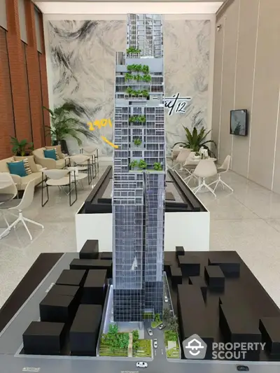 Modern high-rise building model with sleek design and green terraces in a stylish showroom.