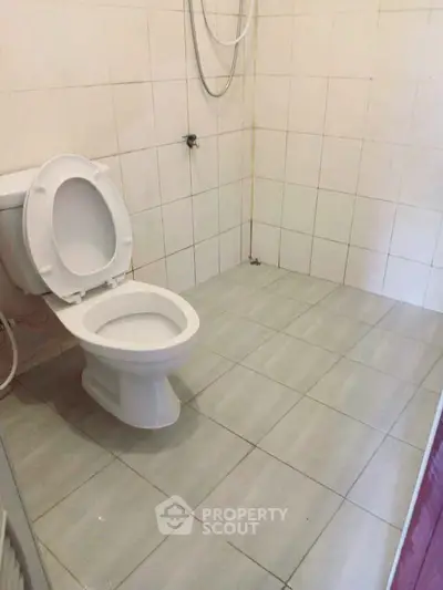 Spacious bathroom with tiled flooring and modern toilet fixture.