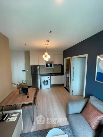Modern living room with open kitchen, featuring sleek appliances and stylish decor.
