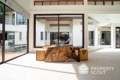 Luxurious modern living room with stunning wooden table and large windows overlooking pool area.