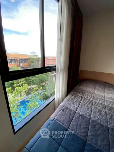Cozy bedroom with large window offering a pool view, perfect for relaxation.