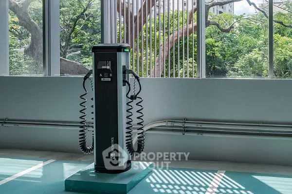 Modern electric vehicle charging station in eco-friendly building with lush greenery view.