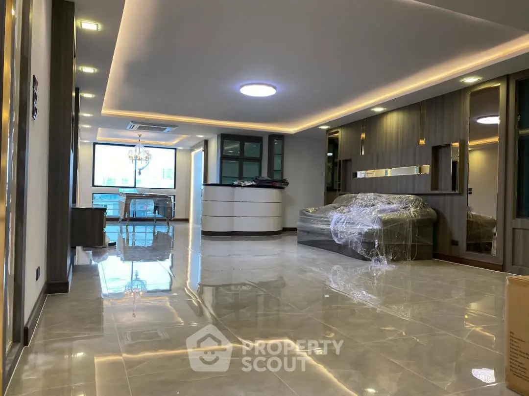 Spacious modern living room with elegant lighting and glossy tiled floors in a luxury apartment.