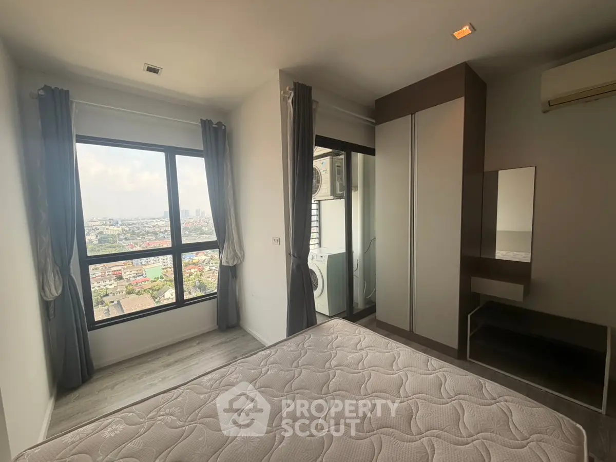 Modern bedroom with large windows offering stunning city views and ample natural light.