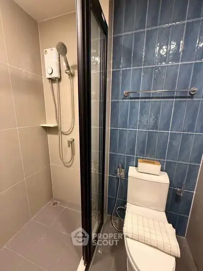 Modern bathroom with shower and toilet, featuring blue accent tiles and sleek design.