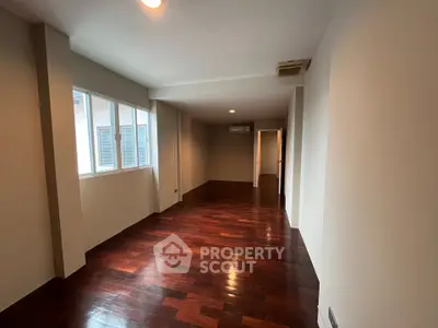 Spacious room with wooden flooring and ample natural light, perfect for versatile living arrangements.