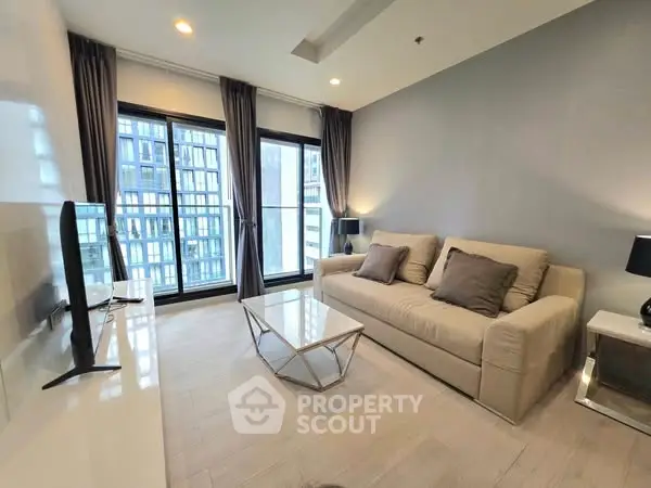 Modern living room with large windows and stylish furniture in a high-rise apartment.