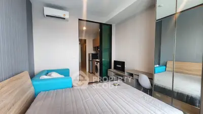Modern bedroom with mirrored closet and compact living area in a stylish apartment.