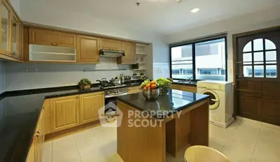 Spacious kitchen with wooden cabinets, island, and washing machine, perfect for modern living.