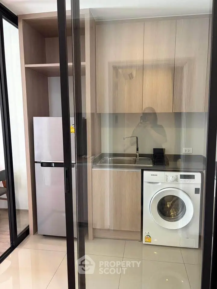Modern kitchen with washing machine and fridge in sleek apartment