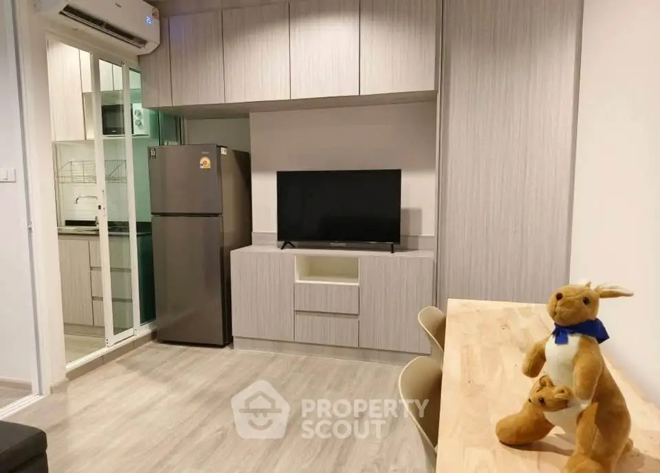 Modern living room with sleek furniture and open kitchen layout, featuring a cozy dining area and stylish decor.