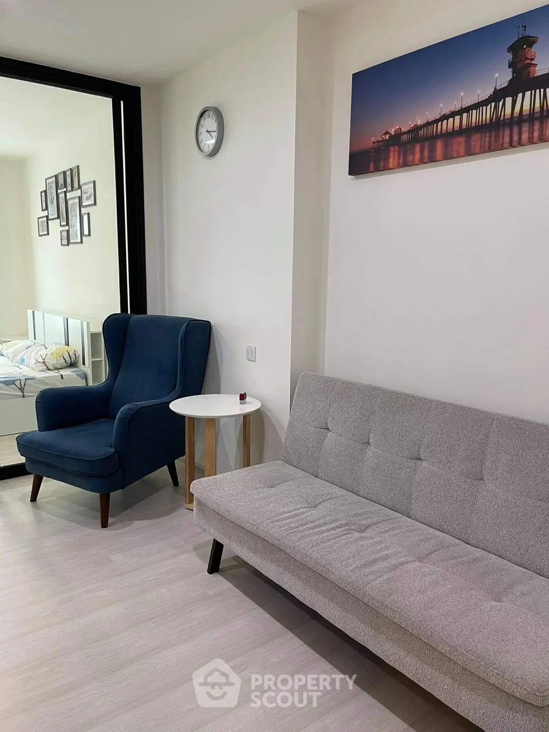Modern living room with stylish furniture and wall art, featuring a cozy armchair and sleek sofa.