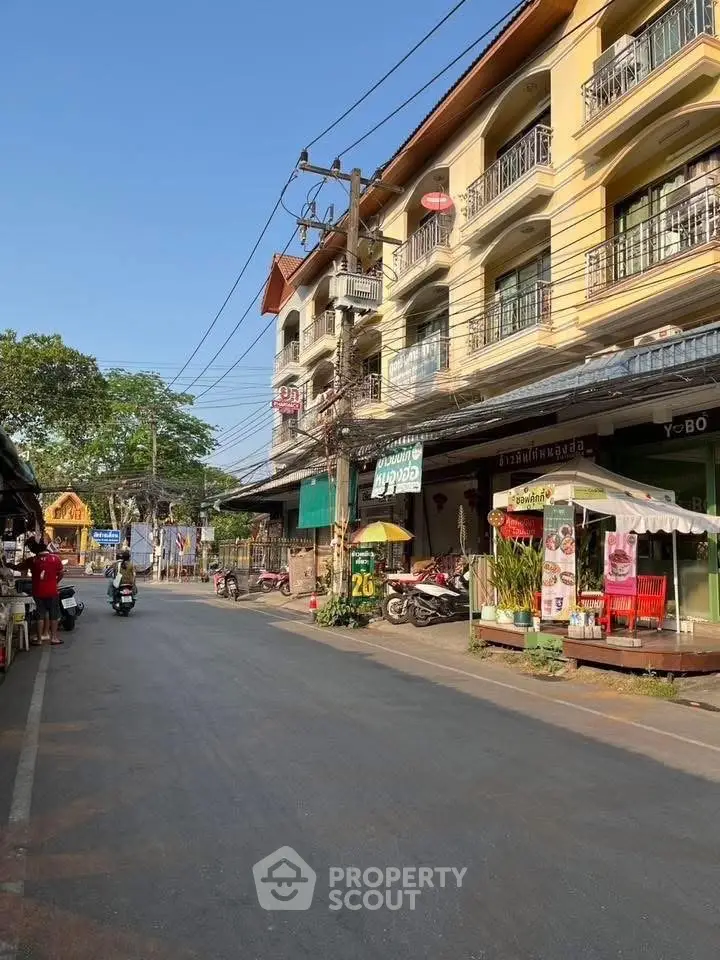 Charming street view of a residential building with shops and balconies, ideal for urban living.
