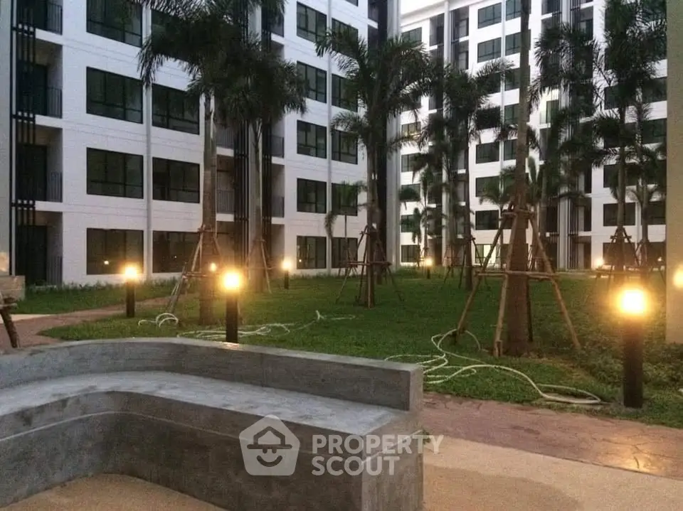 Modern apartment complex with lush garden and ambient lighting in the courtyard.