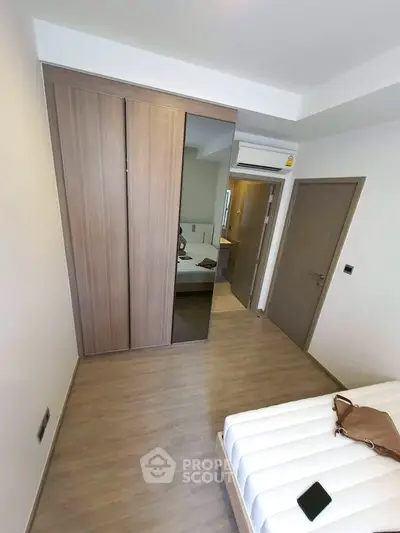 Modern bedroom with sleek wooden wardrobe and cozy bed in a stylish apartment.