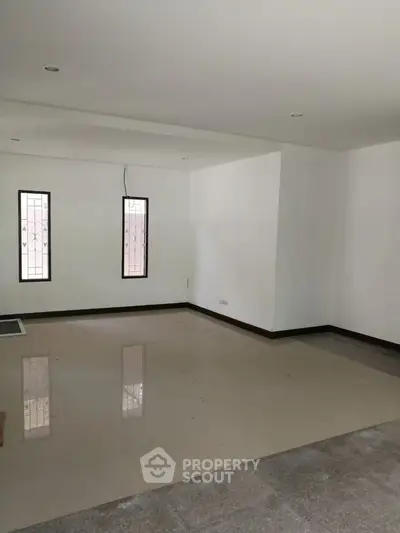 Spacious unfurnished living room with large windows and tiled flooring.