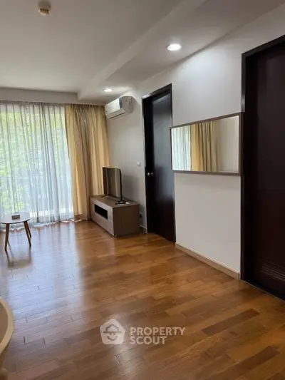 Modern living room with wooden flooring, large window, and sleek furniture.