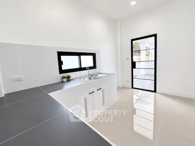 Modern minimalist kitchen with sleek countertops and large window for natural light.