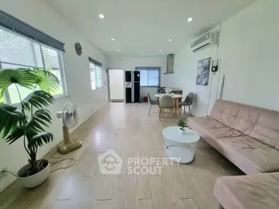 Spacious living room with modern decor and natural light, featuring a cozy sofa and dining area.