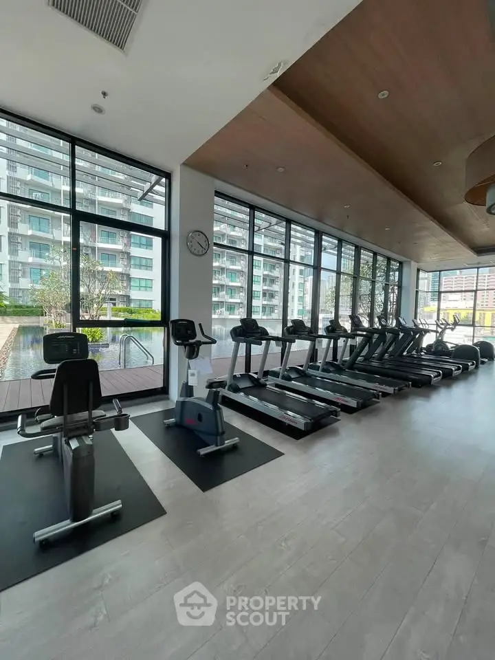 Modern gym with treadmills and large windows in luxury apartment building