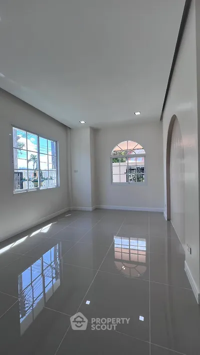 Spacious modern living room with glossy tiled floors and large windows for natural light.