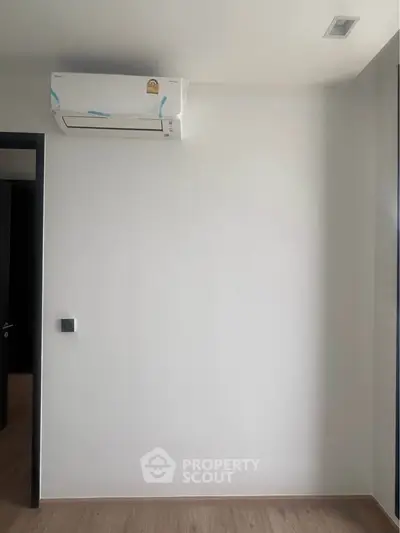 Minimalist room with air conditioning and wooden flooring, ideal for modern living.
