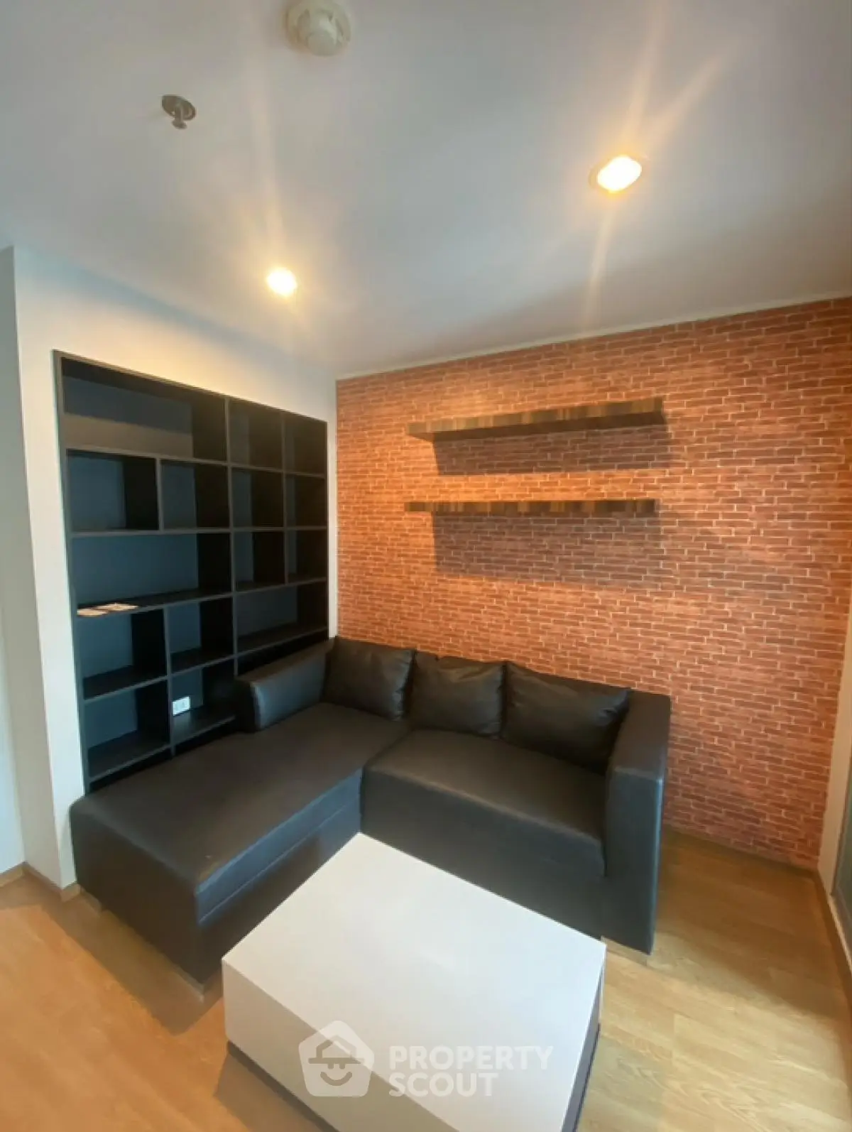 Modern living room with black sofa and brick accent wall