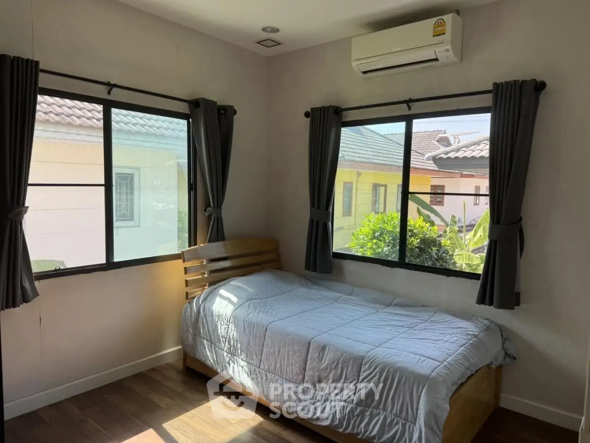 Cozy bedroom with natural light and air conditioning, perfect for relaxation.