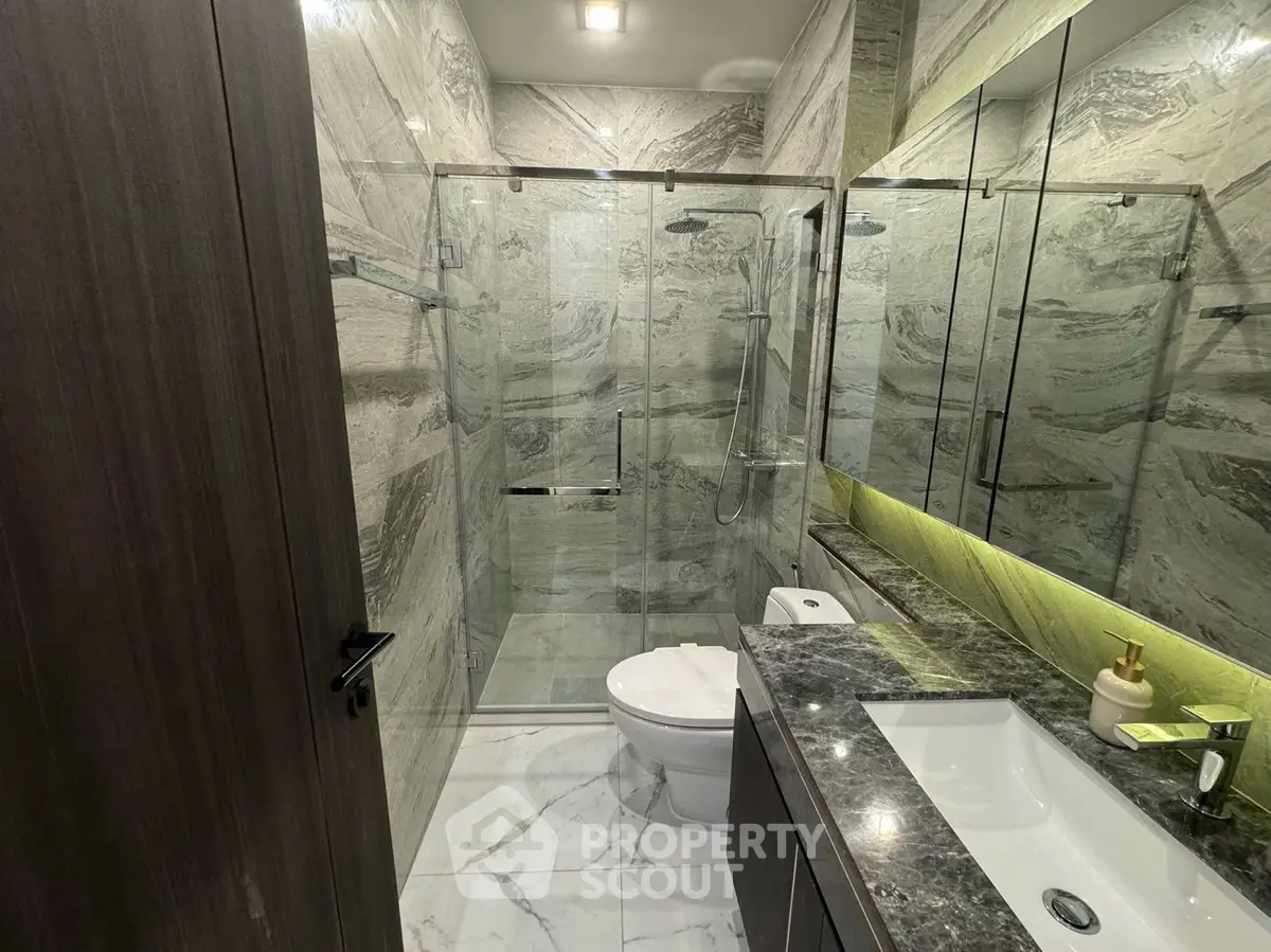 Luxurious modern bathroom with marble tiles and glass shower enclosure