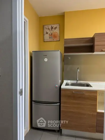 Modern kitchen with sleek fridge and stylish cabinetry in cozy apartment.