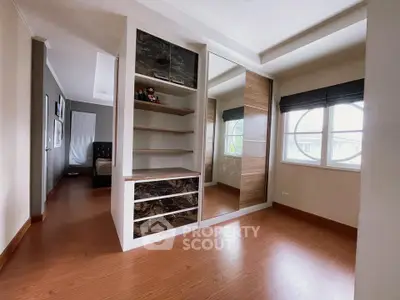 Spacious bedroom with elegant wooden flooring and built-in wardrobe, featuring large windows for natural light.